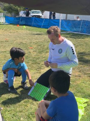 Coach prioritizing Long Term Athletic Development in Youth Sports,. professional soccer coach teaching children how to play soccer. Coach is with a group of 4year olds in their soccer class