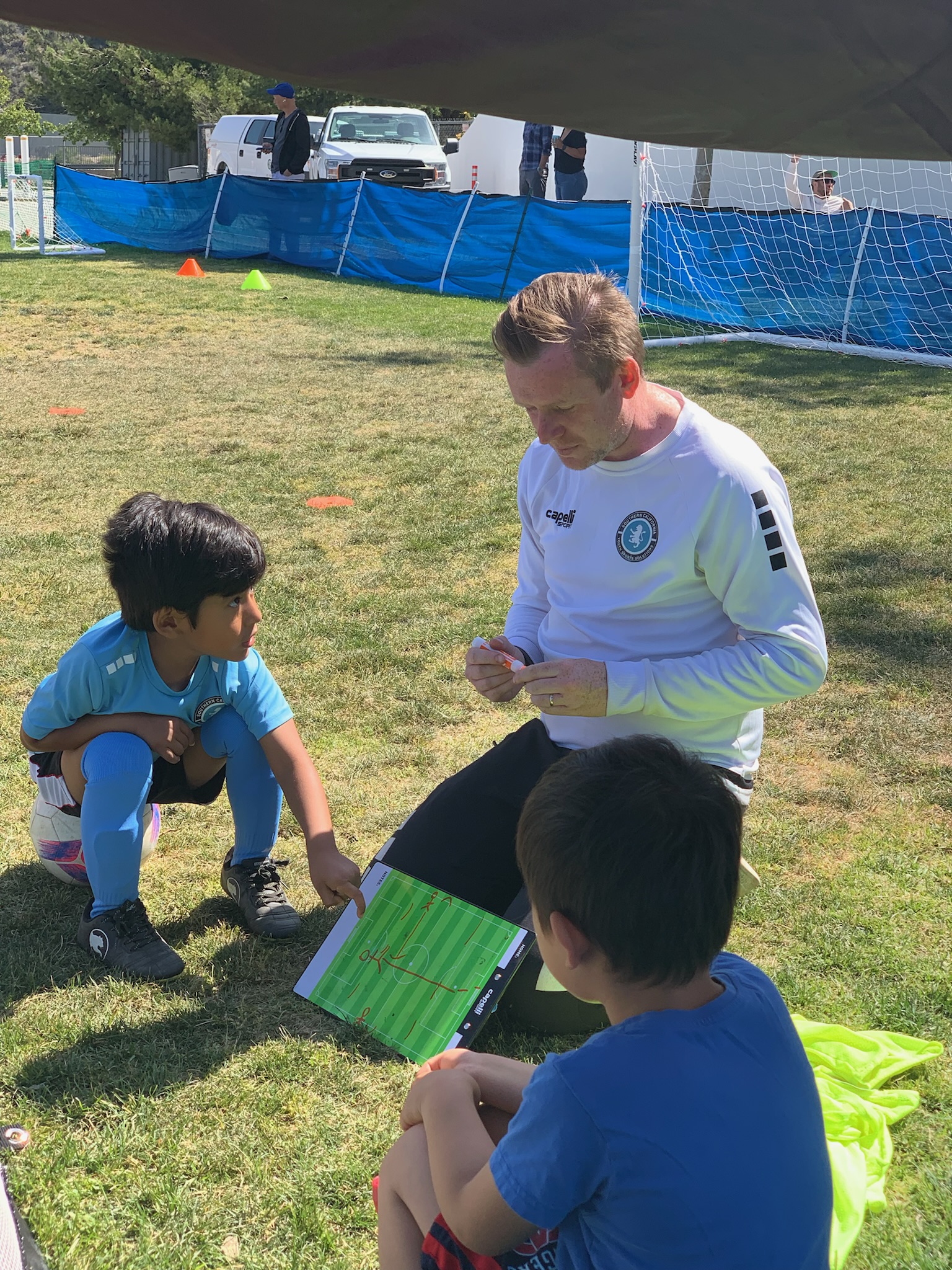 Coach prioritizing Long Term Athletic Development in Youth Sports,. professional soccer coach teaching children how to play soccer. Coach is with a group of 4year olds in their soccer class