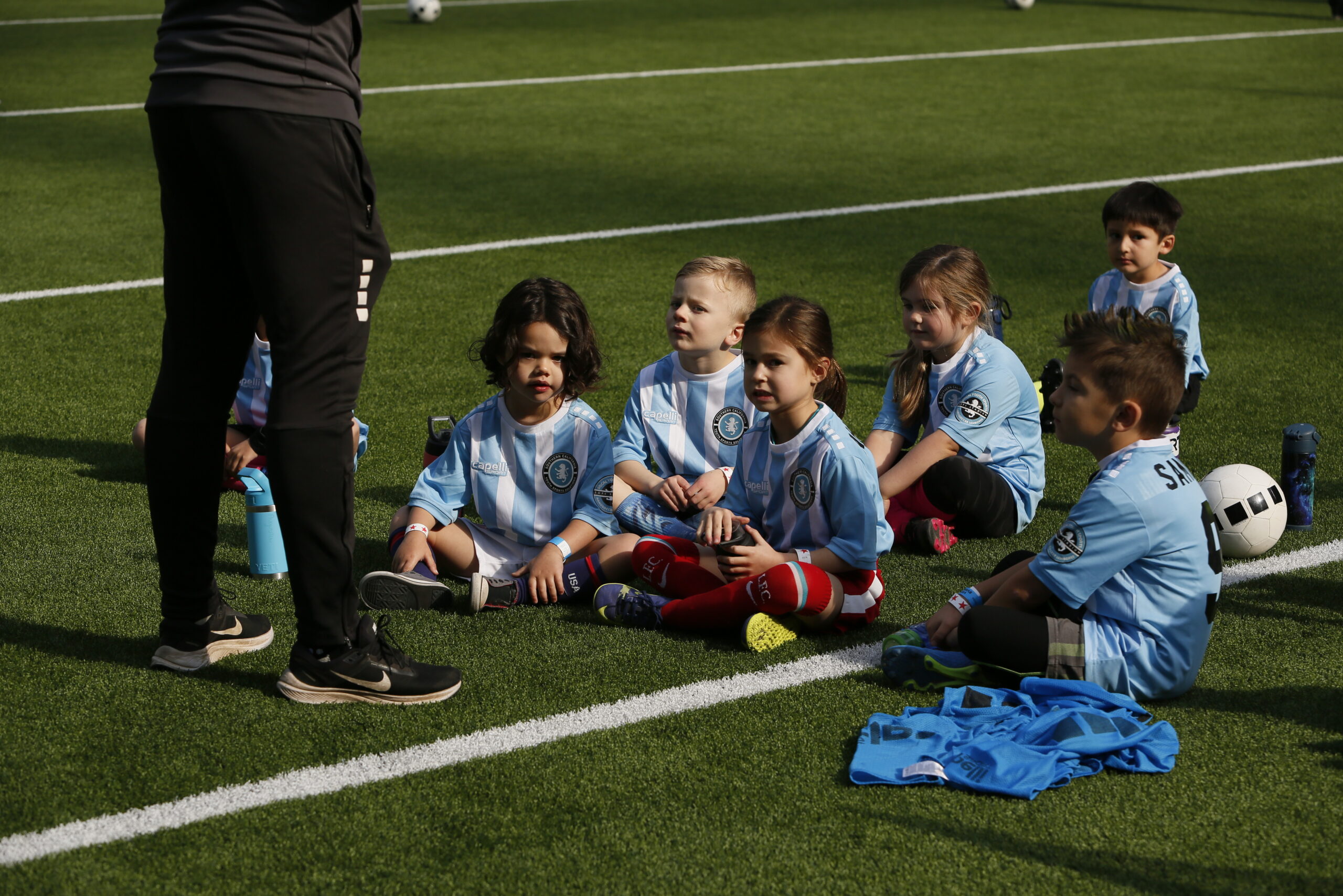 soccer class children. kids listening t their professional soccer coach at their soccer class