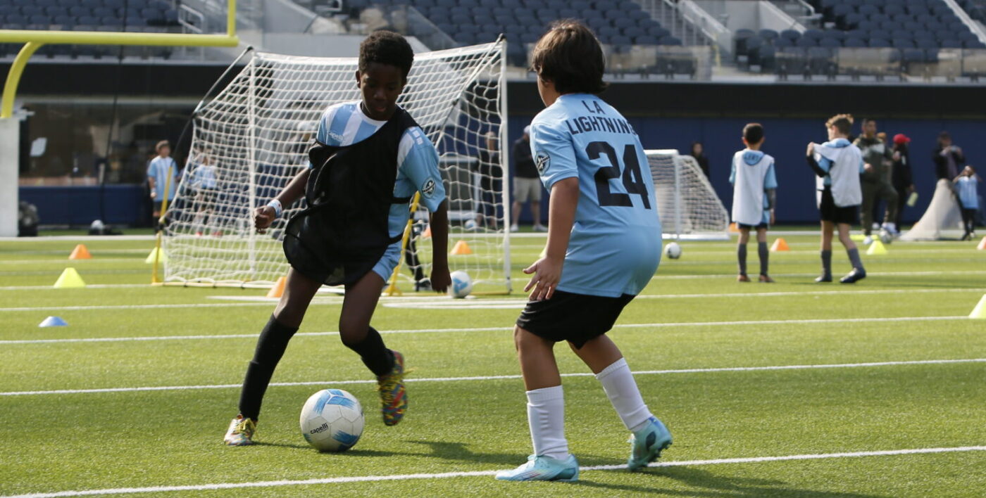 two boys playing soccer in their soccer class. two ten year old boys being professionally coached in soccer